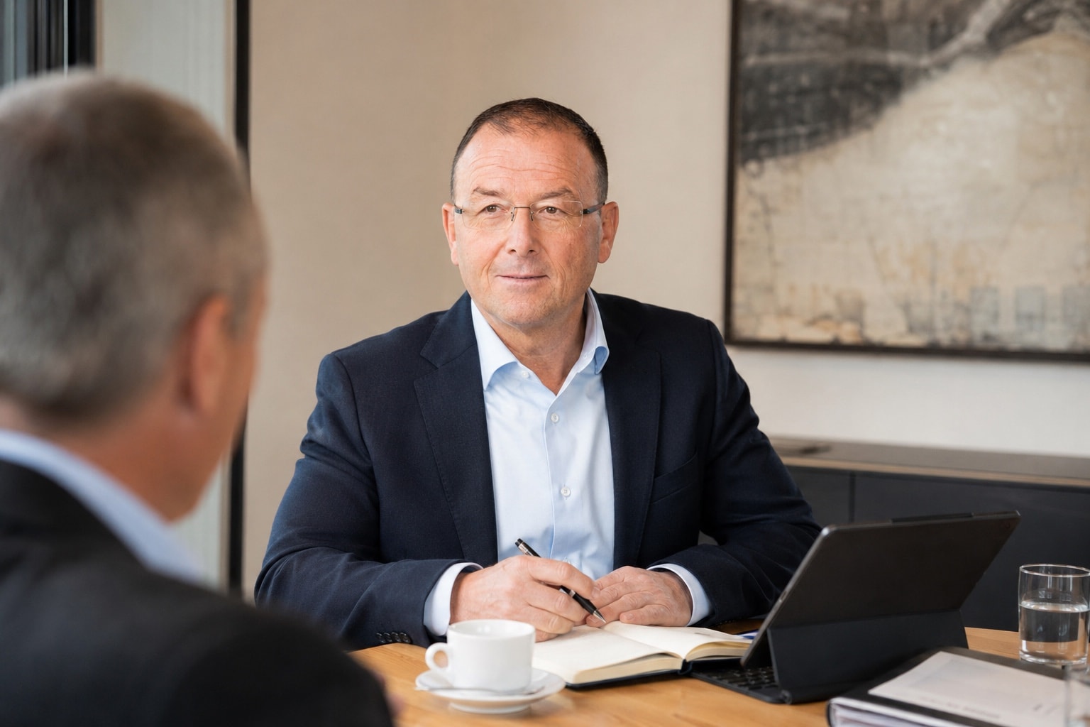 Marco Quinter im Gespräch am Besprechungstisch mit Tablet und Notizen